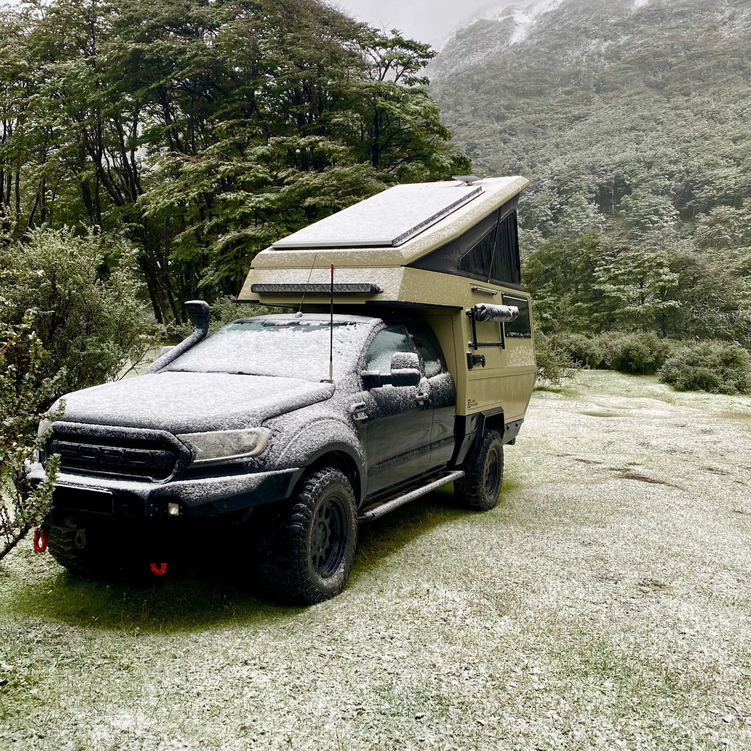 Pickup camper met poptop in de sneeuw, winter kamperen tijdens het overlanden
