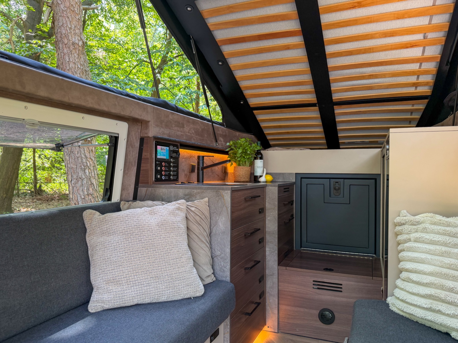 Interieur van de Land Roamer Pioneer camper met hefdak open, geparkeerd in het bos
